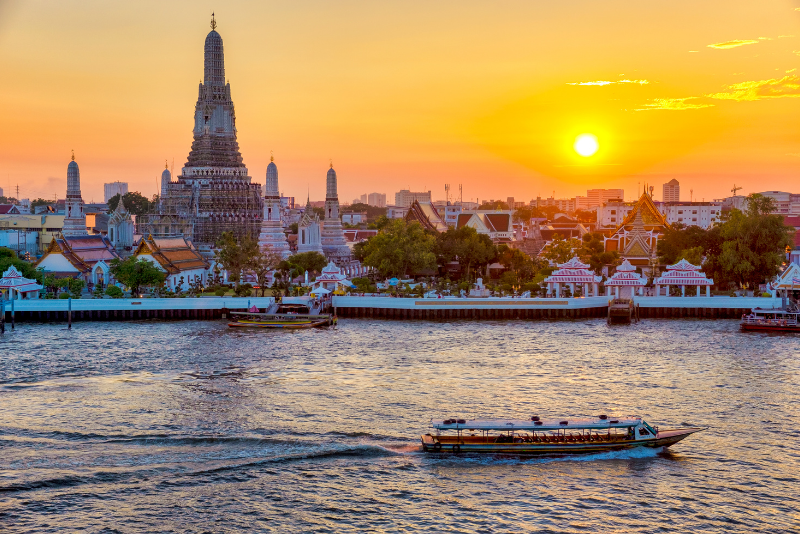 Palace in Bangkok seen across a river with the sun setting