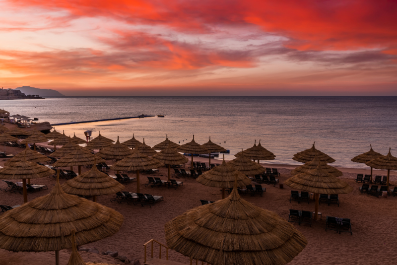 A beach in Hurghada with beach umbrellas and a sunset